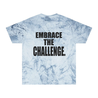 A blue tie-dye t-shirt with a textured pattern reminiscent of a medieval shirt, featuring a motivational message in bold black letters that reads "Embrace the Challenge" on the back.